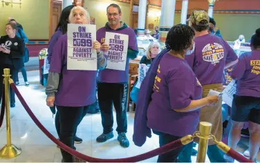  ?? AARON FLAUM/HARTFORD COURANT ?? Jen Carr, an employee at Network Inc., holds a sign as members of SEIU 1199 protest Monday inside the state Capitol as legislator­s prepare to vote on the state budget.