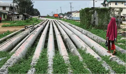  ??  ?? In crisis: A girl walks on a gas pipeline running through okrika community near nigeria’s oil hub city of Port Harcourt. A wave of attacks and accidents have hit infrastruc­ture, taking nigeria’s output down to 20-year lows. — Reuters