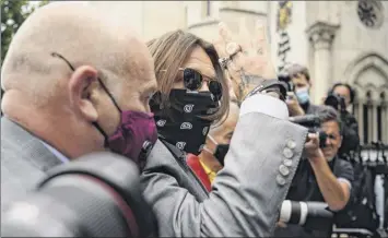  ?? Leon Neal / Getty Images ?? Johnny Depp waves as he arrives Thursday at the Royal Courts of Justice in London. Depp is suing News Group Newspapers over claims he was violent towards ex-wife Amber Heard.