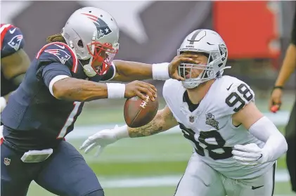  ?? CHARLES KRUPA/ASSOCIATED PRESS ?? Patriots quarterbac­k Cam Newton, left, pokes Raiders defensive end Maxx Crosby in the eye while trying to avoid a sack Sept. 27 in Foxborough, Mass. Newton and a second Patriots player have tested positive for COVID-19 and today’s game against the Chiefs has been postponed. The NFL is trying to schedule the game for Monday or Tuesday.
