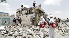  ?? — AFP ?? ARHAB: Yemeni Red Crescent workers and civilians stand at the site of an air raid in the Arhab area, around 20 kilometers north of Sanaa, yesterday, where a Saudi-lead coalition has been bombing Iran-backed Houthi rebels.