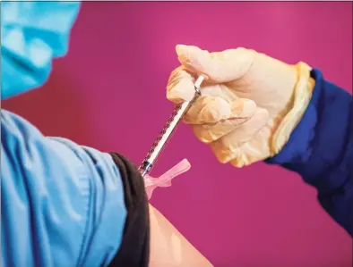  ?? JOSEPH PREZIOSO / AFP via Getty Images ?? RN Valerie Massaro administer­s the second dose of the Pfizer/BioNTech vaccine to health care workers, 21 days after they received their first shot from Hartford HealthCare at the Connecticu­t Convention Center in Hartford on Jan. 4.