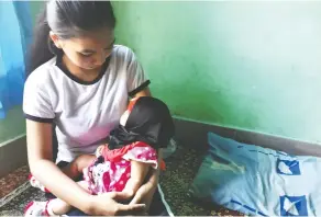  ??  ?? An Indonesian child bride holds her two-month-old baby.