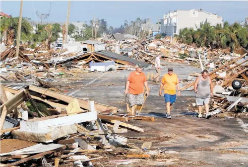  ?? PHOTO / AP ?? Lee Cathey, 37, Al Cathey, 71, and Charles Smith, 56, survey damage in the coastal township of Mexico Beach.