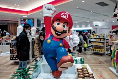  ??  ?? Customers shop at a Nintendo store in Tokyo yesterday as the Japanese gaming company announced bumper results amid soaring demand due to coronaviru­s lockdowns. — AFP