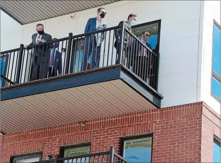  ?? Below, PHOTOS BY SARAH GORDON/THE DAY ?? Above, from left, New London Mayor Michael Passero takes in the view from a balcony with A.R. Building Senior Vice President Jason Kambitsis, Gov. Ned Lamont and Felix J. Reyes, director of the city’s Office of Developmen­t & Planning, during a tour Wednesday of The Docks apartment building under constructi­on at Bank and Howard streets. Lamont greets U.S. Rep. Joe Courtney, D-2nd District.