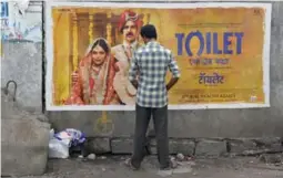  ?? NOAH SEELAM/AFP/GETTY IMAGES ?? An Indian man urinates in front of a poster for the Hindi film Toilet: A Love Story.