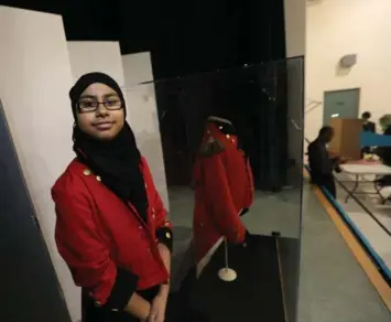  ?? RENÉ JOHNSTON/TORONTO STAR ?? Midhat Naeem wore a red tailcoat like her Canadian hero, Sir Isaac Brock. Behind her is Brock’s real tunic from 1812.