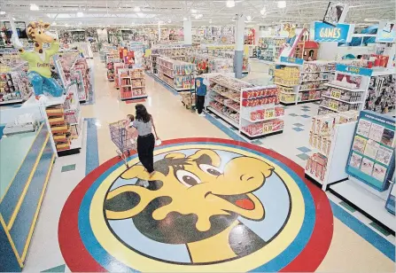  ?? DANIEL HULSHIZER THE ASSOCIATED PRESS FILE PHOTO ?? In this photo from 1996, a woman pushes a shopping cart over a graphic of Toys R Us mascot Geoffrey a a store in Raritan, N.J.