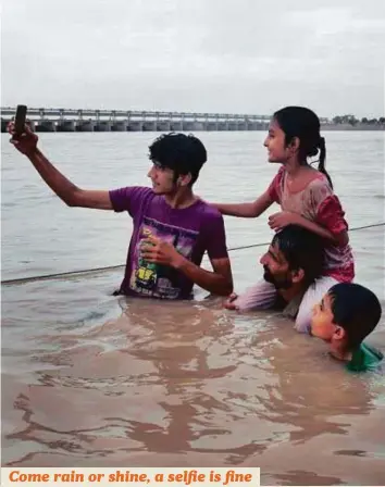  ?? Online ?? People take pictures as they enjoy a dip during rainy weather at the Indus River bank near Ghulam Mohammad Barrage in Jamshoro district, Sindh province.