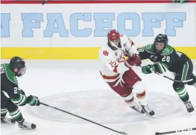  ??  ?? North Dakota’s Hayden Shaw checks Denver’s Troy Terry while UND’s Cole Smith skates in from the left during the first period of Friday’s NCHC Frozen Faceoff semifinal game in Minneapoli­s. Eric Hylden, Grand Forks Herald