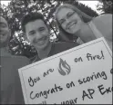 ??  ?? Alex Oseguera, center, is surrounded by Mr. and Mrs. Winterhalt­er. Oseguera holds one of the signs that proclaims a Lodi High student received a five on his or her AP test. It is the first time Lodi High students are being honored with the signs.