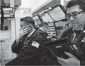  ?? Spencer Platt / TNS ?? Traders work on the floor of the New York Stock Exchange on Tuesday. The Dow Jones Industrial Average fell nearly 800 points.