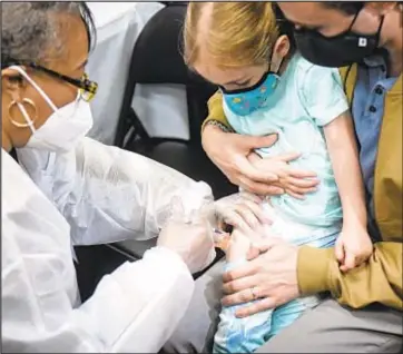  ?? ?? Max Bookman watches as his daughter, Cara, 2, receives her first shot of the Moderna vaccine Wednesday in a Times Square vaccinatio­n hub.