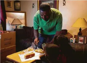  ??  ?? John McClenon serves lunch to his children amid moving boxes last week. McClenon said he has never been late or missed his rent payment there.