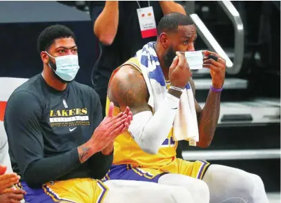  ?? EFE ?? Anthony Davis sentado junto a LeBron James, que se coloca la mascarilla