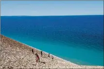  ??  ?? Visitors explore a steep, 400-foot-high sand dune at Stop 9 along the Pierce Stocking Scenic Drive, a seven-mile blacktop road that leads cars and cyclists through the wooded hills and towering dunes at Sleeping Bear Dunes National Lakeshore.