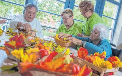  ?? FOTO: JENS BÜTTNER/DPA ?? Gemeinsame­s Basteln, wie hier mit herbstlich-bunten Blättern, gehört zu den Tagespfleg­eangeboten.