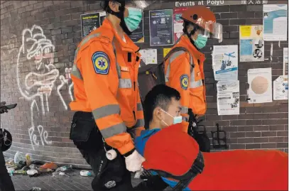  ?? Ng Han Guan The Associated Press ?? Medics evacuate a man from Hong Kong Polytechni­c University on Wednesday. Schools there reopened after a six-day shutdown.