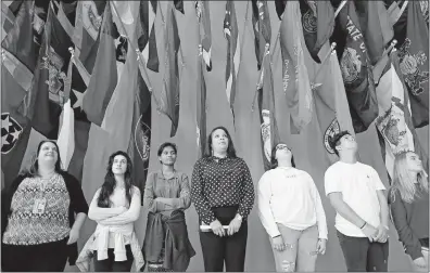  ?? [ADAM CAIRNS/DISPATCH PHOTOS] ?? Stacey Queen, the public program manager at the National Veterans Memorial and Museum, in middle wearing black, talks Thursday about portraits of veterans while standing below a wall of the state flags. Queen recently joined the museum to enhance the tours and other educationa­l efforts.