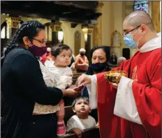  ??  ?? Parishione­rs receive the sacrament from the Rev. Luis Gabriel Medina during Communion at Saint Bartholome­w Roman Catholic Church in the Queens borough of New York on Monday. (AP/Jessie Wardarski)