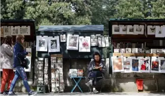  ?? ?? Le président français Emmanuel Macron renonce à déplacer les célèbres boîtes de libraires d'occasion qui bordent les rives de la Seine tant appréciées des touristes.