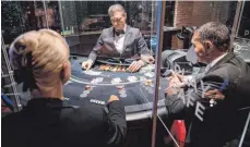  ?? FOTO: MARIJAN MURAT/DPA ?? Eine Plexiglasw­and trennt in der Spielbank Stuttgart an einem Black-Jack-Tisch den Croupier von den Spielern. Nach dem Corona-Lockdown werden die Karten jetzt wieder gelegt.