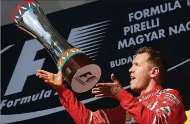  ??  ?? Endlich wieder ein Sieg! Sebastian Vettel jubelt mit dem Pokal, mit dem er seine Wm-führung auf den Verfolger Lewis Hamilton wieder ausgebaut hat. Foto: Laszlo Balogh, Reuters