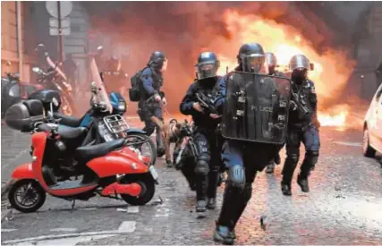  ?? AFP ?? Agentes antidistur­bios corren junto a un automóvil en llamas en los Campos Eliseos