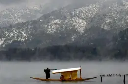  ?? — PTI ?? A boatman clears snow from his Shikara at the Dal Lake in Srinagar on Thursday. Srinagar and other parts of Kashmir have been experienci­ng heavy rain and snowfall, a rare occurrence in April, for the past three days.