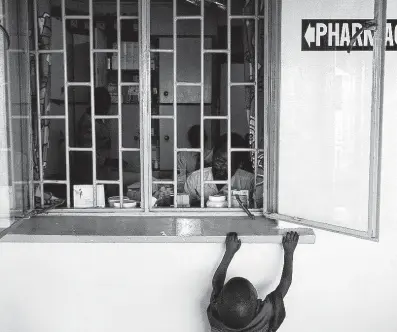  ?? Smiley N. Pool / Courtesy ?? A child reaches up to the pharmacy window while waiting for a prescripti­on to be filled in 2005 at the Paediatric Infectious Diseases Clinic of Mulago Hospital in Kampala, Uganda.