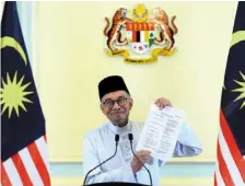  ?? ?? The new team: anwar showing the list of cabinet members during the announceme­nt at the Prime minister’s office. — azhar mahfof/the Star