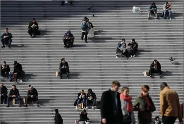  ?? (AP) ?? People are shown in March in the business district of La Defense outside Paris. The European Commission predicts that the eurozone economy will shrink by 7.7% this year.