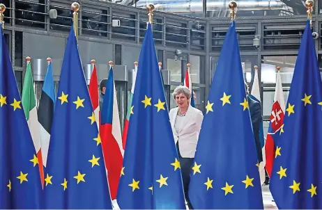  ?? (AFP) ?? This file photo shows Britain’s Prime Minister Theresa May walking behind flags of European Union as she arrives on the second day of the EU leaders’ summit, in Brussels on June 23