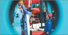  ?? JIN TIAN / FOR CHINA DAILY ?? Middle: Engineers from Baoji Oilfield Machinery, which is affiliated with China National Petroleum Corp, work on the maintenanc­e of the Shenditake
1 well.