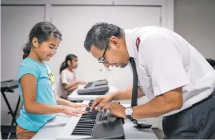  ?? ?? Salvation Army Corps Lt. Ismael Gutierrez helps Ximena Martinez, 9, make an adjustment to her keyboard during practice Wednesday at the Salvation Army.