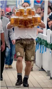  ?? — AP ?? (Below) Oliver Struempfel competes during his world record attempt carrying 27 beer mugs at the traditiona­l festival Gillamoos in Abensberg, Germany, on Sunday.