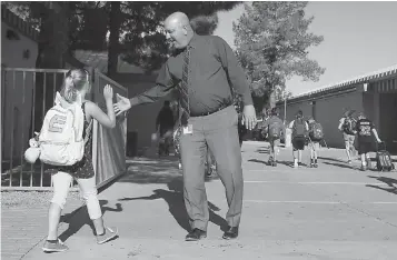  ?? AP Photo/Ross D. Franklin ?? ■ Principal Shawn Duguid welcomes a student back to Oakwood Elementary School after a statewide Arizona teachers’ strike ended Friday in Peoria, Ariz. Hundreds of thousands of Arizona schoolchil­dren returned to classes Friday, a day after state...