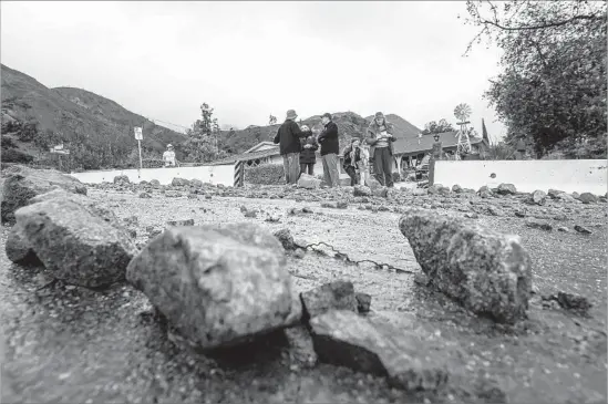  ?? Irfan Khan Los Angeles Times ?? RESIDENTS take a look after a rain-caused slide Friday on Mel Canyon Road in Duarte. Officials warn of mudslides and mudflows when a storm hits Sunday.