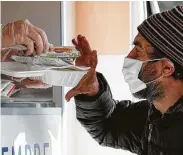  ?? Antonio Calanni / Associated Press ?? A homeless man is given food Saturday in Milan, Italy. A lockdown has closed canteens and shelters.