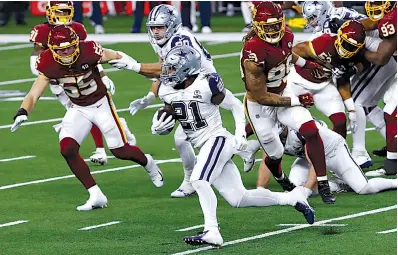  ?? Associated Press ?? ■ In this file photo, Dallas Cowboys running back Ezekiel Elliott carries the ball as Washington Football Team’s Cole Holcomb (55) and Chase Young (99) give chase Nov. 26, 2020, in Arlington, Texas. The teams meet Sunday at Washington.