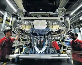  ?? /Reuters ?? Top gear: Porsche employees work on a sports car at the company’s factory in Stuttgart-Zuffenhaus­en in Germany, as the eurozone rides a wave of solid manufactur­ing output.