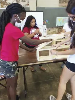  ?? (Special to The Commercial) ?? Alex Foundation intern Janett Solorio of Eudora (back center), camper Ka’Tiyah Young (left) of Eudora and intern Kathy Mondragon (right) of Lake Village put the finishing touches on Ka’Tiyah’s wall ascent house shelf.