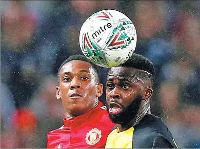  ?? ANDREW YATES / REUTERS ?? Manchester United's Anthony Martial is beaten to a header by Burton Albion's Hope Akpan during their English League Cup thirdround match at Old Trafford on Wednesday. United cruised past the Brewers 4-1.