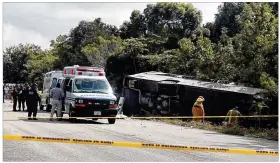  ?? CONTRIBUTE­D BY NOVEDADES DE QUINTANA ROO ?? An ambulance parks next to an overturned bus Tuesday in Mahahual, Quintana Roo state, Mexico. The bus was carrying cruise ship passengers to Mayan ruins when it flipped over on a highway early Tuesday.