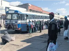  ?? AFP ?? Commuters exempt from the lockdown and deemed essential service providers form a queue to board a bus in Harare, Zimbabwe on Monday.