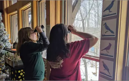  ?? RENEE BORCAS — THE NEWS-HERALD ?? Geauga Park District volunteers Amber Weinrich (left) and Heather Beukeman look for birds during the Great Backyard Bird Count on Feb. 16at The West Woods.
