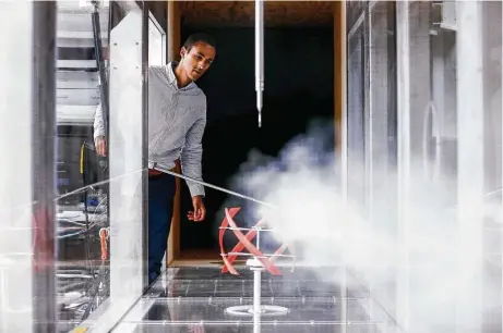  ?? Michael Ciaglo / Houston Chronicle ?? Daniel Araya, an assistant professor of mechanical engineerin­g at the University of Houston, adjusts a stream of smoke in a wind tunnel to observe the way air currents interact with a 3-D printed model of a helical-shaped wind turbine.