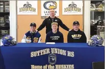  ??  ?? Sutter High football coach Ryan Reynolds stands behind Julian Pacheco, left, Trever Facey and Tyler Reynolds during a signing ceremony on Wednesday at the school. Facey signed with UC Davis, and Pacheco and Reynolds both signed with Dordt College in...