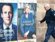  ??  ?? A municipal police officer walks near election campaign posters for French centrist presidenti­al candidate Emmanuel Macron (left) and far-right candidate Marine Le Pen, in Saint Jean Pied de Port, southweste­rn France, last Friday.